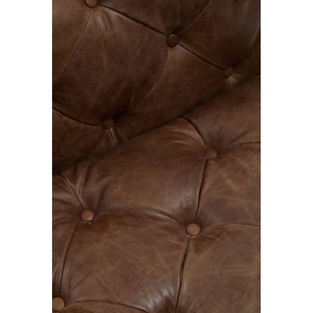 Close-up of a brown leather tufted armchair with button details.