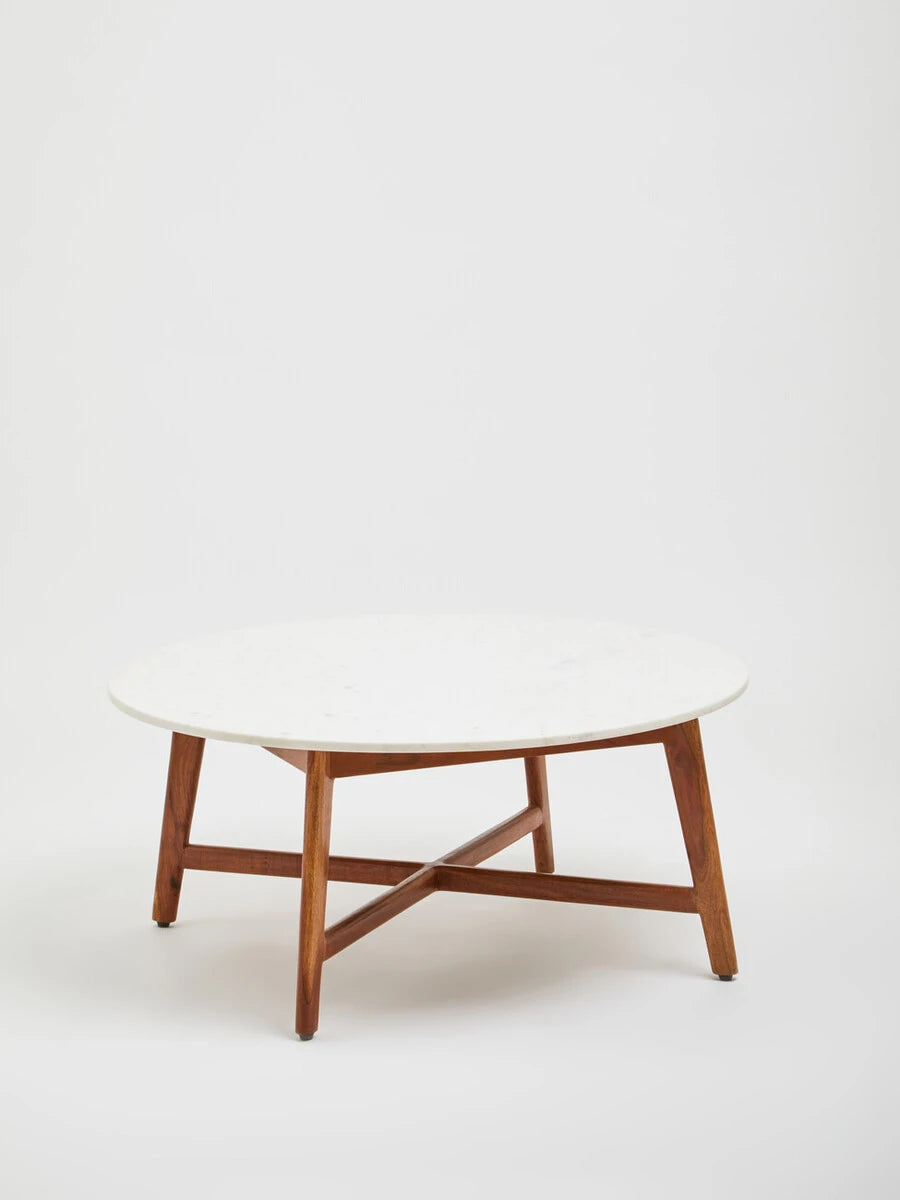 Alder round white marble coffee table against a plain backdrop