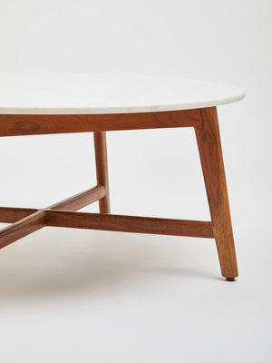 Detail of the Alder coffee table's marble top and angled acacia wood leg