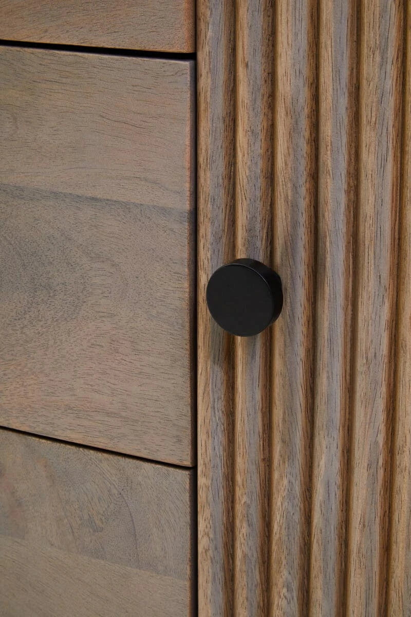 Close-up of a round black knob on a reeded door of the Hawthorn Grey Oval Sideboard.