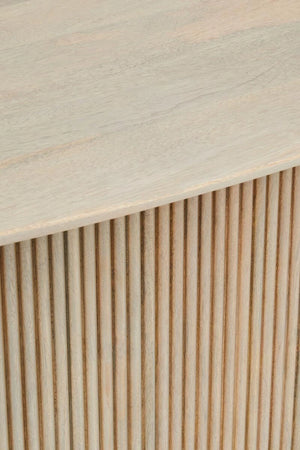 Close-up of the curved edge of the Hawthorn Grey dining table top above the fluted mango wood base.