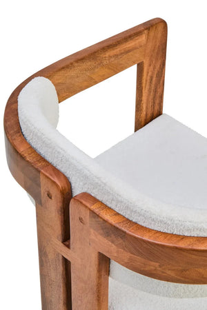 Close-up of the curved mango wood frame of the Hawthorn Dining Chair wrapping around the bouclé backrest.