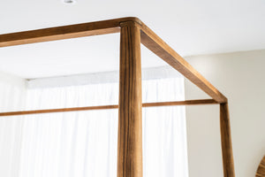Close-up of a tapered reclaimed teak post and canopy rail on the Ashcombe Four Poster King Size Bed.