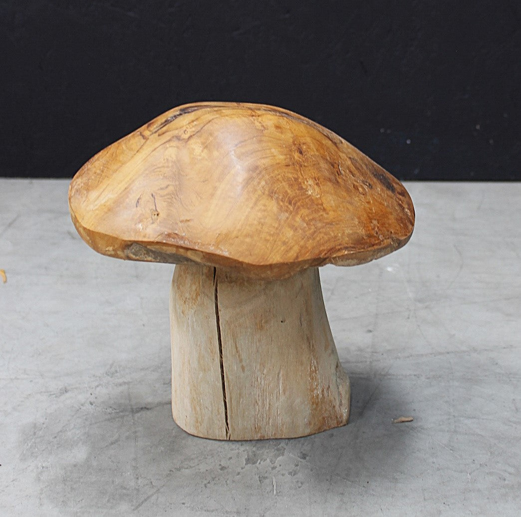 Wooden mushroom-shaped ornament on a grey surface with a black background