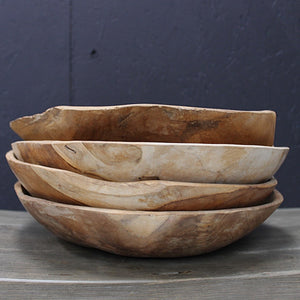 Stack of four wooden bowls on a dark surface with a dark background