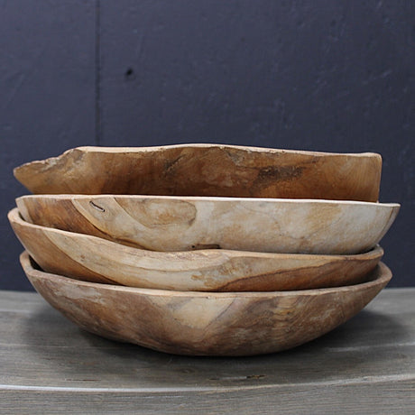 Stack of four wooden bowls on a dark surface with a dark background