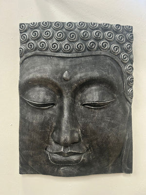 Decorative wall art of a Buddha face with a textured finish on a plain background