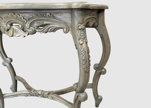 An ornate carved console table with a distressed gray and silver finish, shown against a plain light gray background.