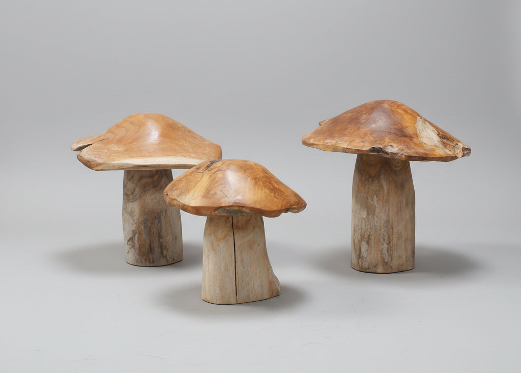 Three wooden mushroom-shaped ornaments on a grey background