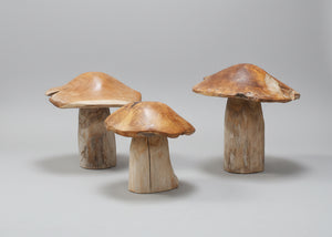Three wooden mushroom-shaped ornaments on a grey background