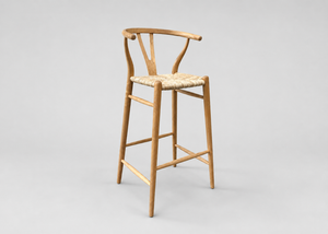 A light natural wood bar stool with a woven straw seat, shown from a three-quarter angle against a neutral light gray background.