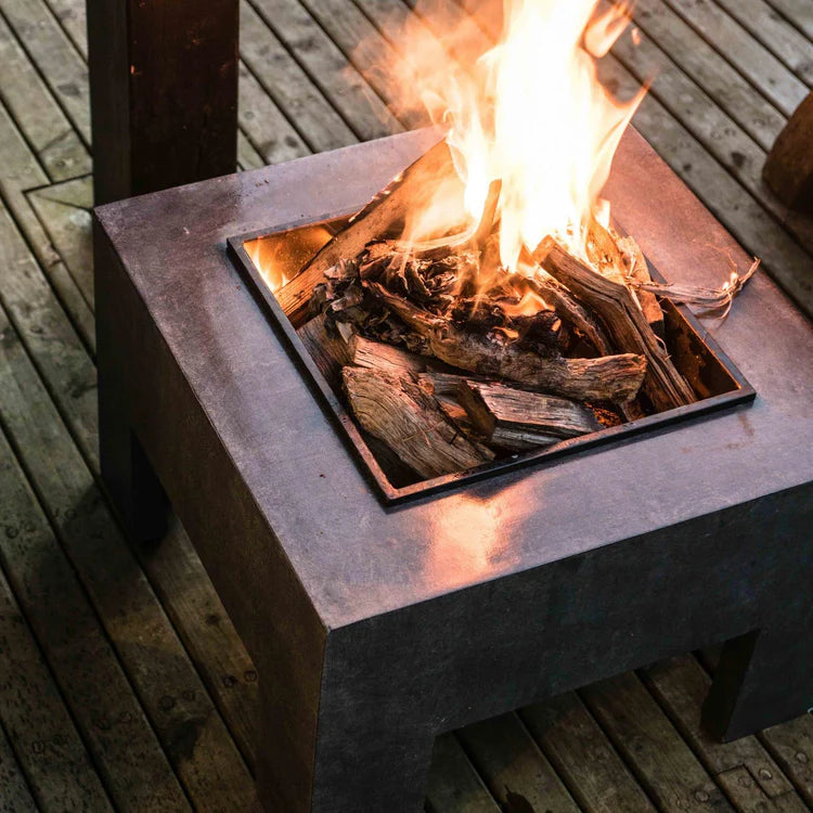 Fire pit with flames and burning wood on a wooden deck