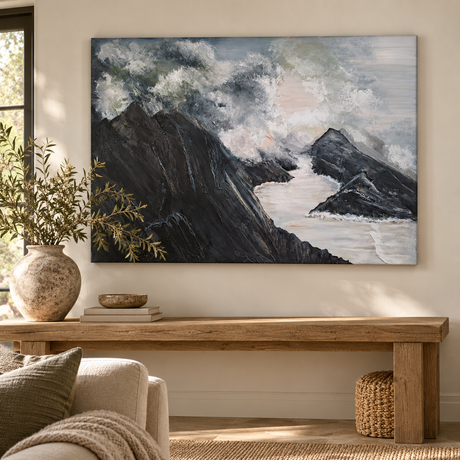 After The Storm painting of dark mountain peaks and white surf above a reclaimed wood console table with a stone vase of olive branches