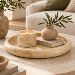 Alba Cream Marble Round Tray styled with a candle, neutral book and small textured vase on a stone coffee table.