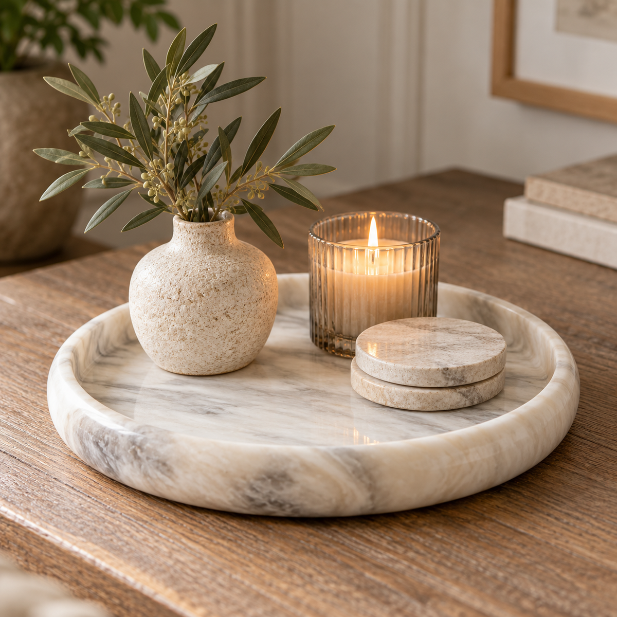 Alba White Marble Round Tray with natural grey veining, styled with a ceramic vase, greenery, candle and marble coasters on a rustic wooden table.