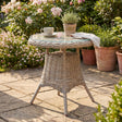 Wicker side table with a cup and plant on a patio