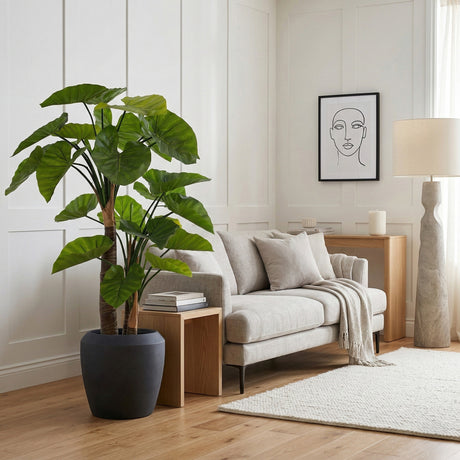 Modern living room with a grey sofa, potted plant, and side table.