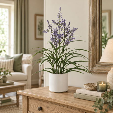 Artificial Lavender Plant in a white pot on an oak chest of drawers, beside a wooden mirror, a lit candle and a stack of books