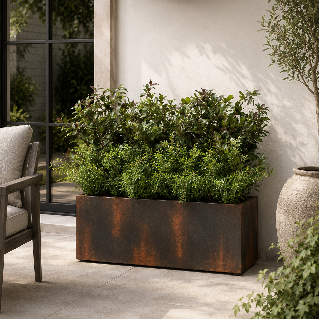 Rust-colored metal planter with green plants on a patio
