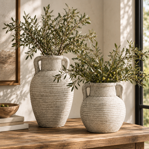 Two Athena Amphora Pots in different sizes holding olive branches on a wooden sideboard by a window