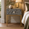 Axis One Drawer Bedside Table with Bone Inlay styled beside a bed with a table lamp, a vase of olive branches and books