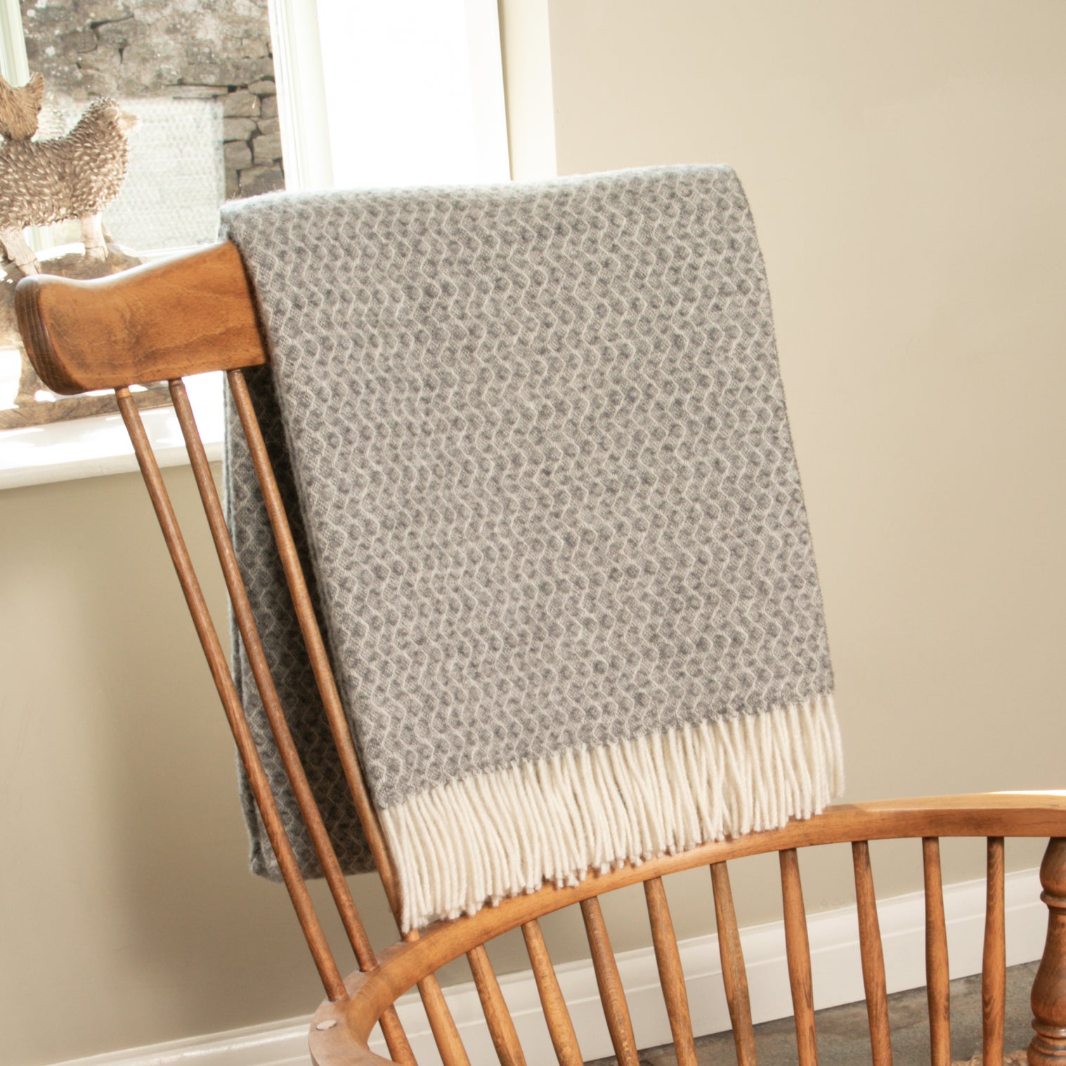 A woollen throw over the back of a wooden chair.