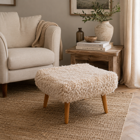Beige armchair with a beige shearling sheepskin footstool in a cosy living room setting.
