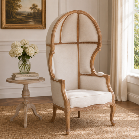 Wooden chair with cream cushion in a room with a side table and flowers.