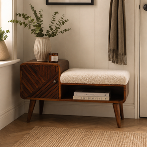 A mid-century modern wooden entryway bench with a cream bouclé seat cushion, shown in a styled home entryway next to a window with a potted eucalyptus and a hanging scarf.