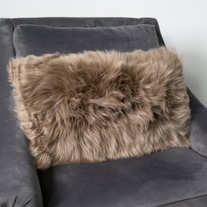 Rectangular Light Brown Sheepskin Cushion on a grey velvet armchair
