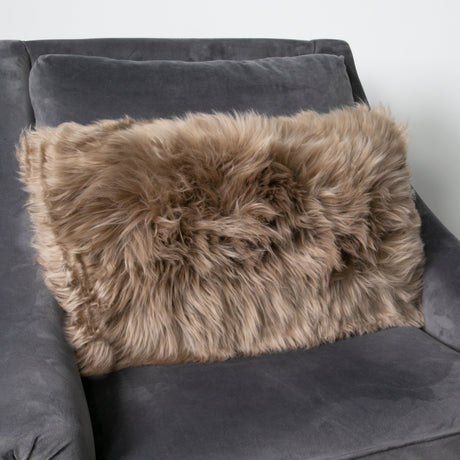 Rectangular Light Brown Sheepskin Cushion on a grey velvet armchair