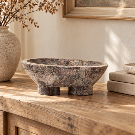 Cairn Forest Green Marble Pedestal Bowl on a rustic oak sideboard, beside linen books and a stoneware vase of dried flowers.