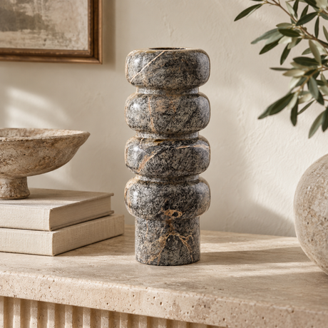 Cairn Forest Green Marble Vase with its stacked pebble silhouette, styled on a fluted stone console beside linen books, a stone bowl and olive branches.