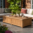A rectangular wooden outdoor coffee table with lift-up storage, styled on a patio with a sofa, greenery, and tableware in a real environment.