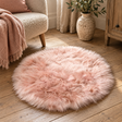 Circular Pink Sheepskin Rug on a wooden floor beside a cream armchair with a pink throw