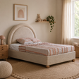 Cream boucle upholstered double bed with striped bedding in a cosy bedroom setting.