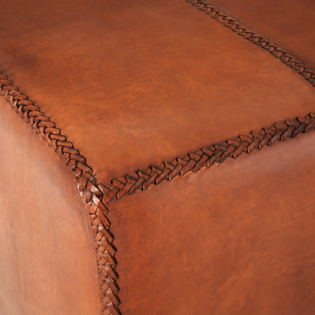 Close-up of a brown leather ottoman with braided edge.