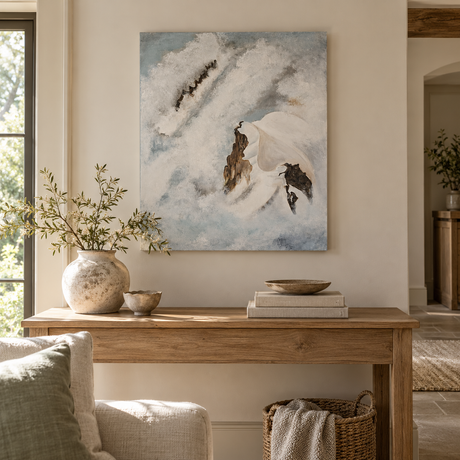 Echoes of Silence painting of snowy mountain peaks above a reclaimed wood console table with a stone vase of olive branches and stoneware bowls