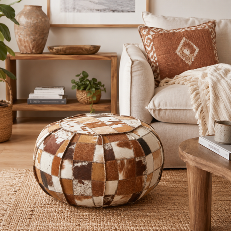 Forge patchwork leather pouffe on a woven rug by a cream linen sofa with boho decor