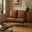 Forma brown leather two seater sofa in a cosy room setting with textured walls and a woven rug