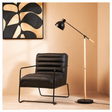 Modern black armchair with a floor lamp against a beige wall with abstract art.