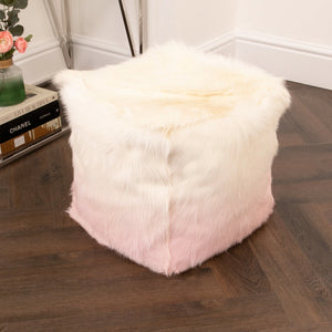 Fluffy pink and white cube-shaped ottoman on a wooden floor.