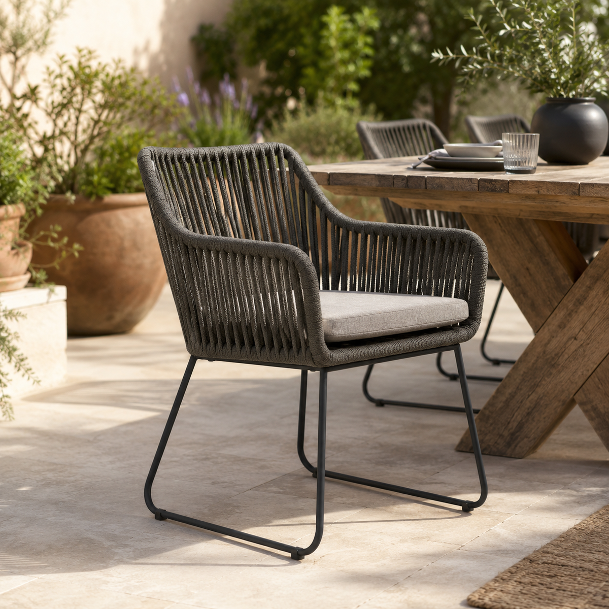 Outdoor dining setting with wicker chair and wooden table in a garden.