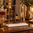 Loxley white marble and gold finish bar tool stand on a sideboard beside decanters and glasses