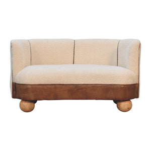 A beige and brown sofa with a boucle texture and buffalo hide leather seat, supported by round wooden legs.