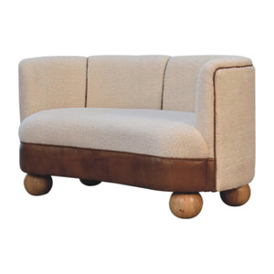 A cream boucle sofa with buffalo leather detail and round mango wood legs