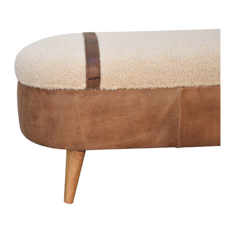 Close up of a beige boucle seat bench with brown buffalo leather straps and a wooden base with four legs.
