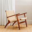 Armchair with mahogany wood frame and natural woven back and seat against a neutral background