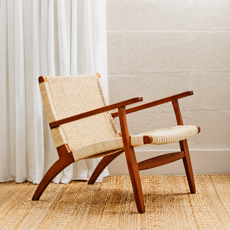 Armchair with mahogany wood frame and natural woven back and seat against a neutral background