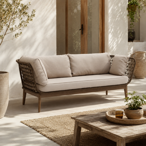 Outdoor patio with a wicker sofa, wooden coffee table, and potted plants.